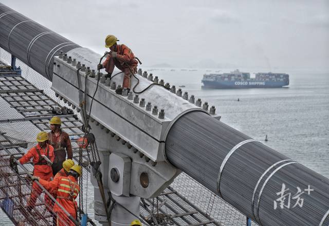 正在施工中的建設(shè)者身后，海上船舶往來不斷。  