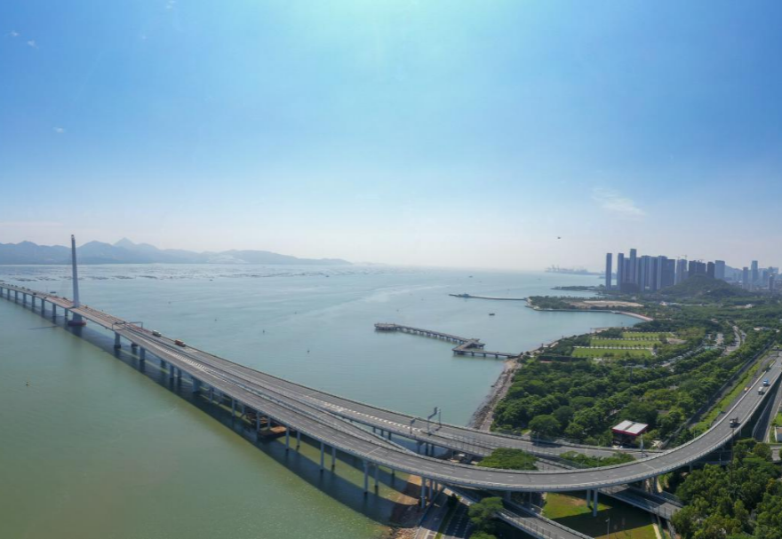 深圳灣大橋是繼羅湖、皇崗和沙頭角之后深圳第4條跨境通道，全長5545米，設(shè)南北兩個通航橋，主跨分別為210米和180米。大橋連接深圳蛇口與香港元朗，為中國公路干線網(wǎng)中唯一與香港連接的高速公路大橋，也是廣深沿江高速公路的咽喉。廣州與香港的距離因該橋建成通車縮短至100千米。大橋深圳側(cè)獨塔斜拉橋塔采用向香港側(cè)傾斜的斜塔，與香港側(cè)斜拉橋的橋塔向深圳側(cè)傾斜互相對應(yīng)，寓意深港兩地手牽手走向一起。圖為深圳灣大橋。