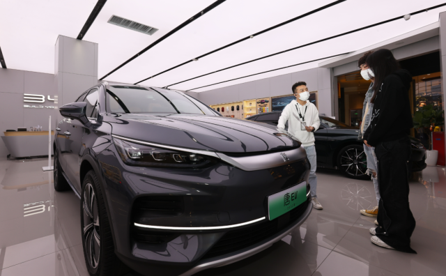 比亞迪店內(nèi)，一名銷售人員（左）正在向兩位顧客介紹車輛信息。深圳特區(qū)報記者 楊浩翰 攝