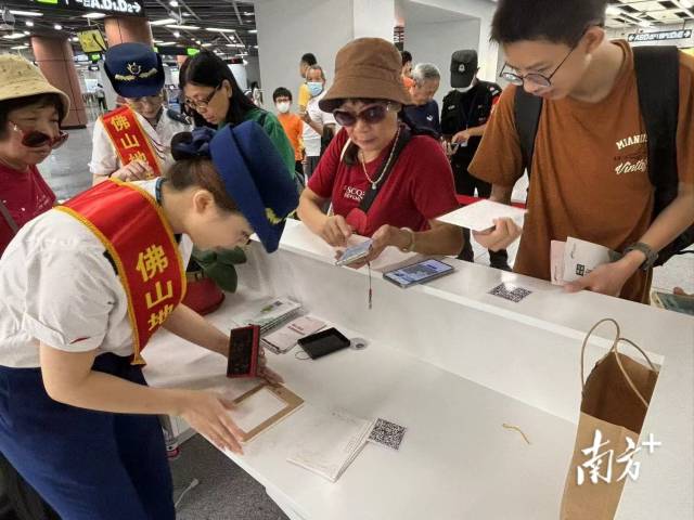市民在桂城站便民服務(wù)臺(tái)用明信片蓋章打卡。龍西男 攝