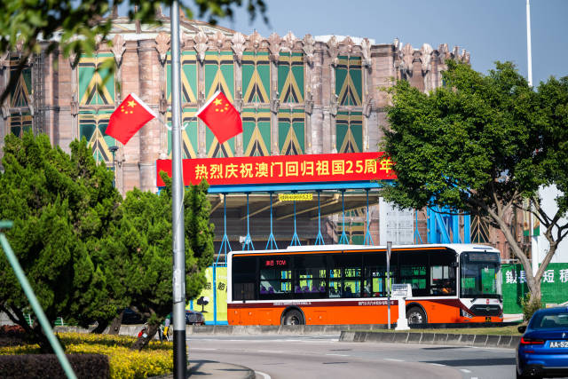 12月17日，車輛從慶祝澳門回歸祖國25周年橫幅旁駛過。新華社記者 朱煒 攝