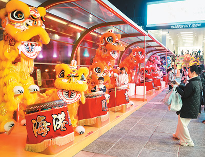 近日在香港維多利亞港畔，游客和醒獅合影。新華社記者 褚萌萌攝