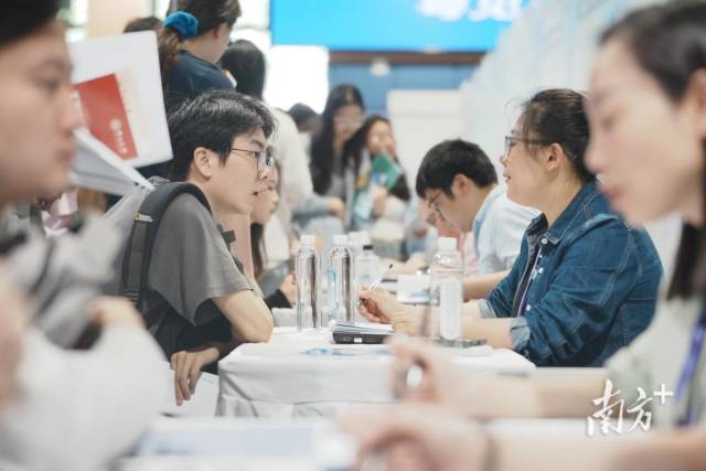 “百万英才汇南粤”武汉招聘会现场火爆，企业招聘展位座无虚席，面试洽谈对接需求。